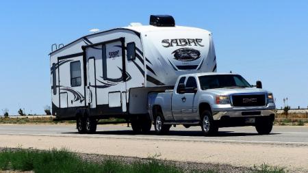 A van towing a fifth-wheel camper